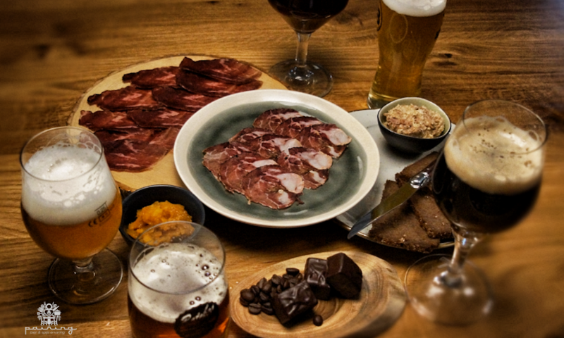 Verschillende glazen bier op tafel met allerlei hapjes op plankjes en bordjes erbij